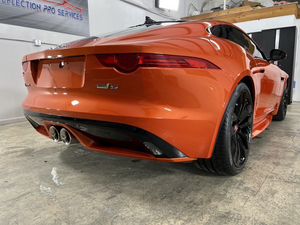 A red jaguar f type is parked in a garage.