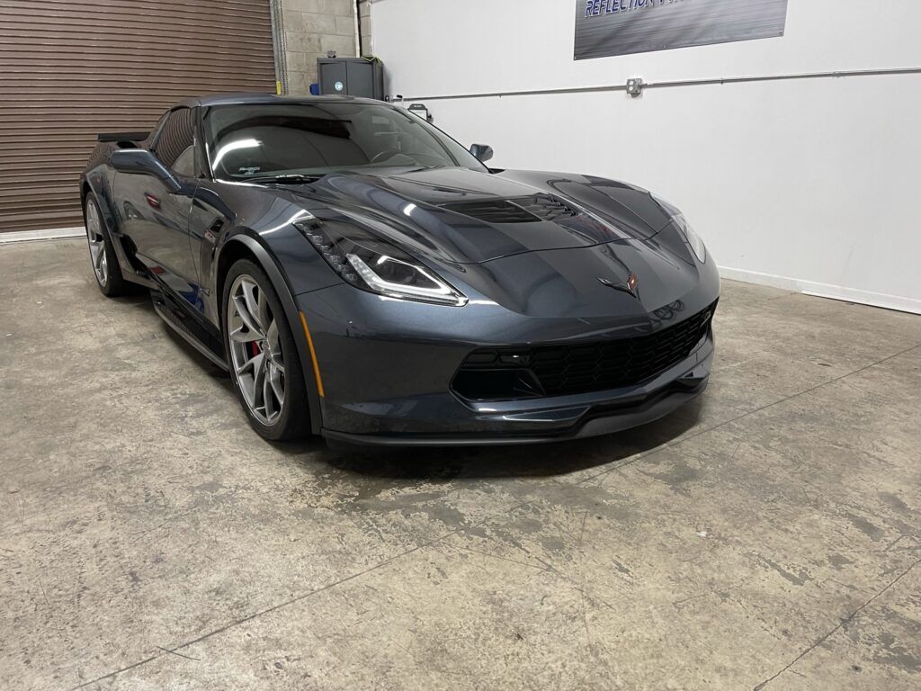 A black sports car is parked in a garage.