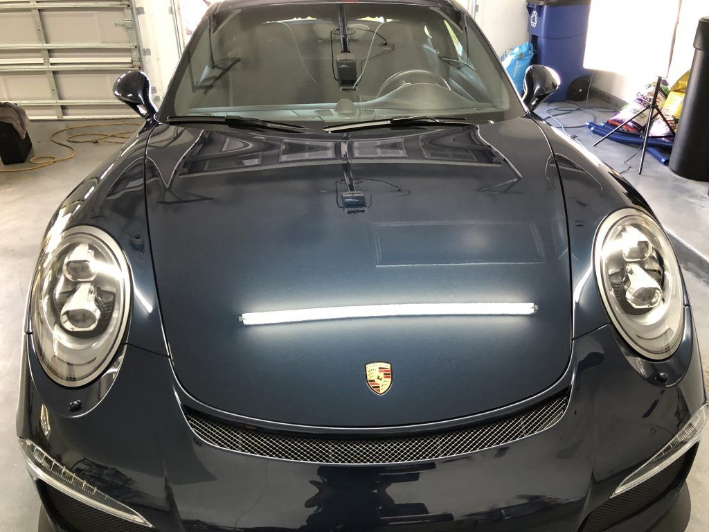 A black porsche 911 is parked in a garage.