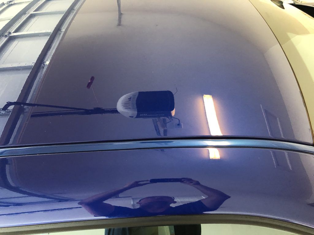 A person is reflected in the hood of a car