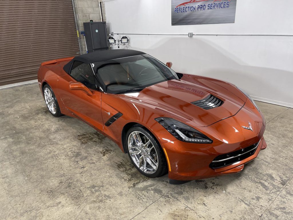 A red corvette convertible is parked in a garage.