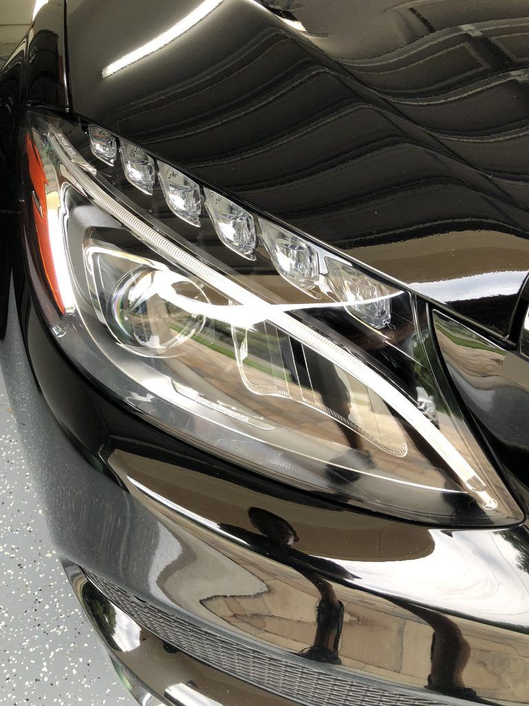 A close up of a black car 's headlight in a garage.