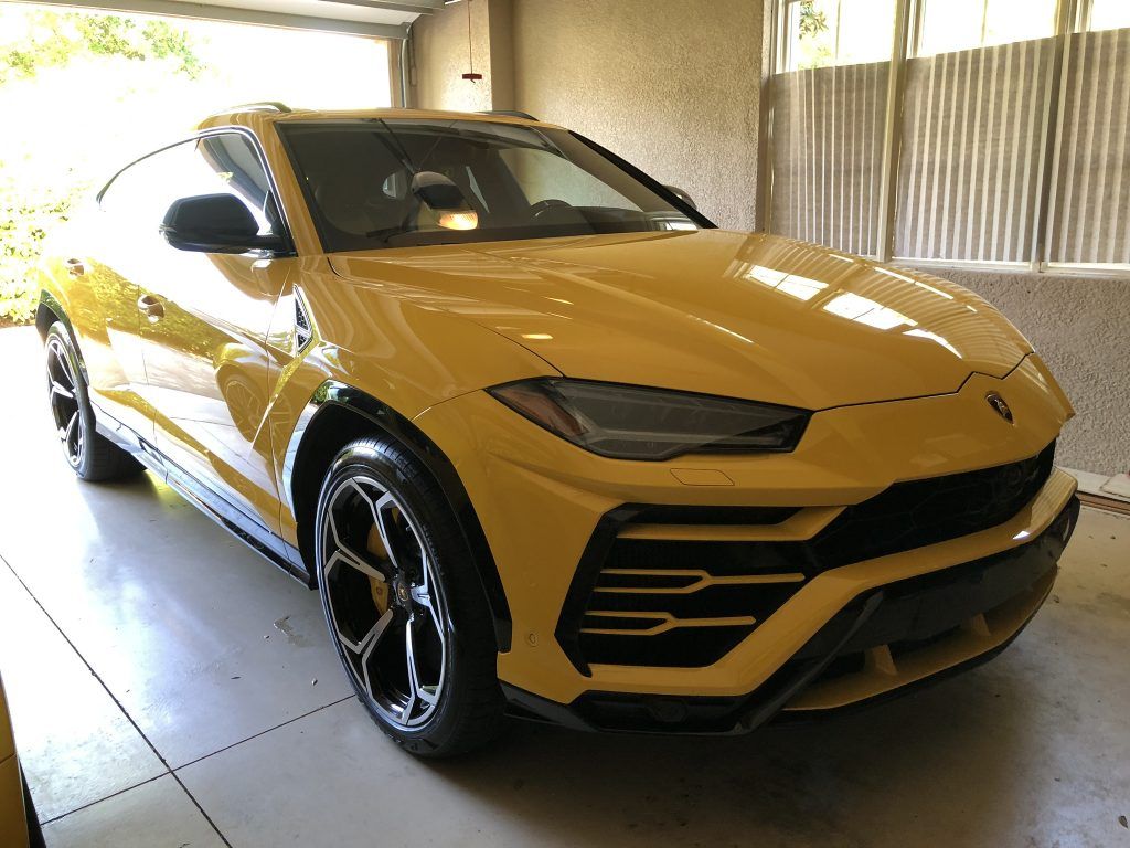 A yellow lamborghini urus is parked in a garage.