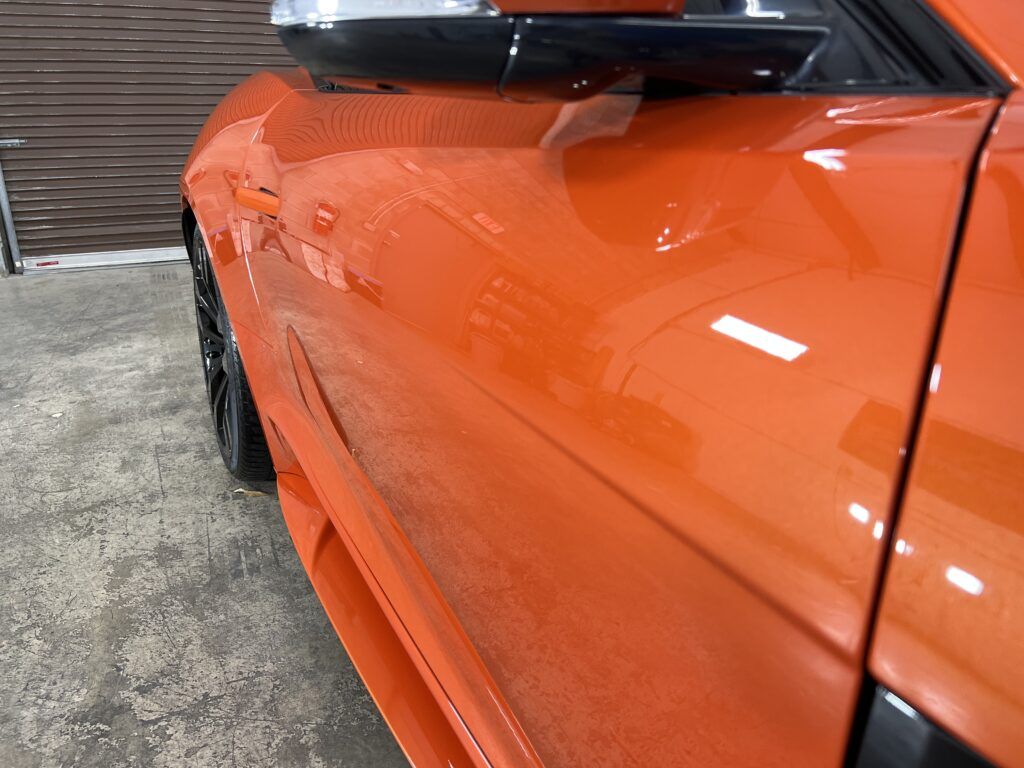 A close up of the side of an orange car