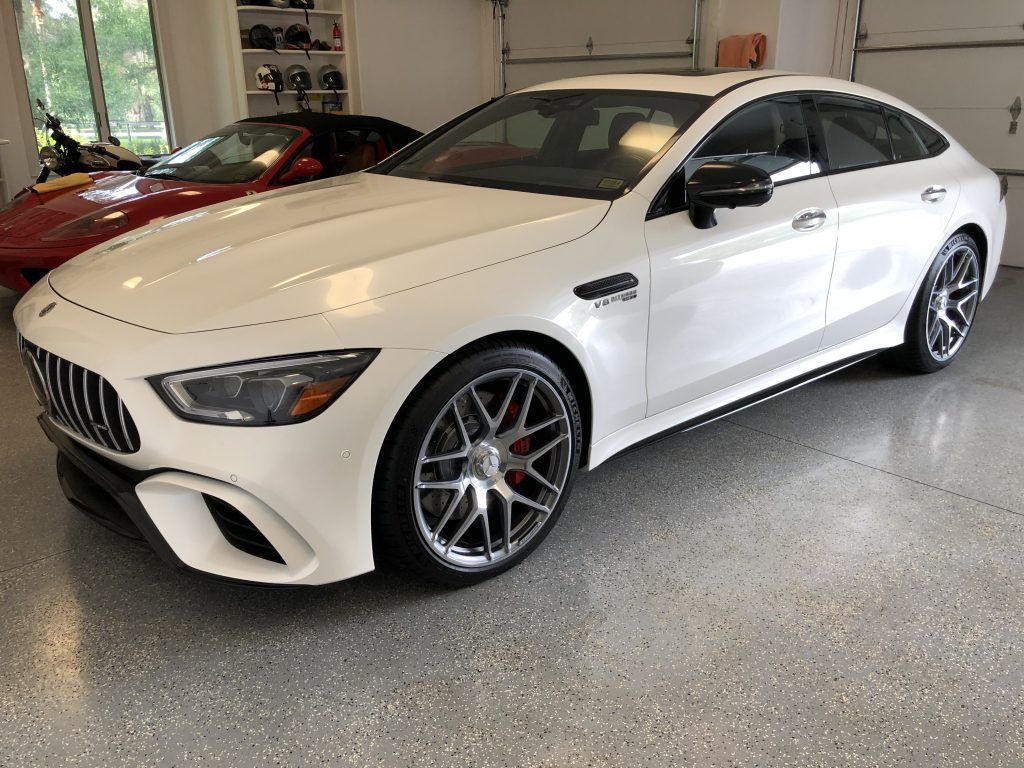 A white mercedes amg gt 63 s is parked in a garage.