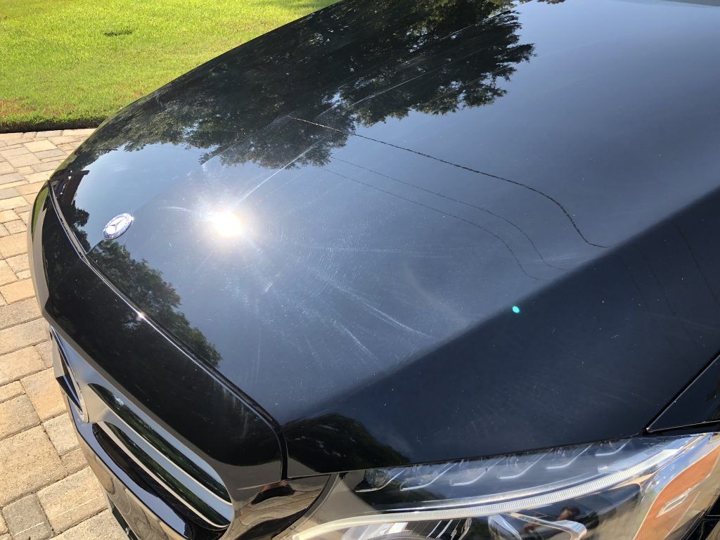 A close up of a black car 's hood and headlights.