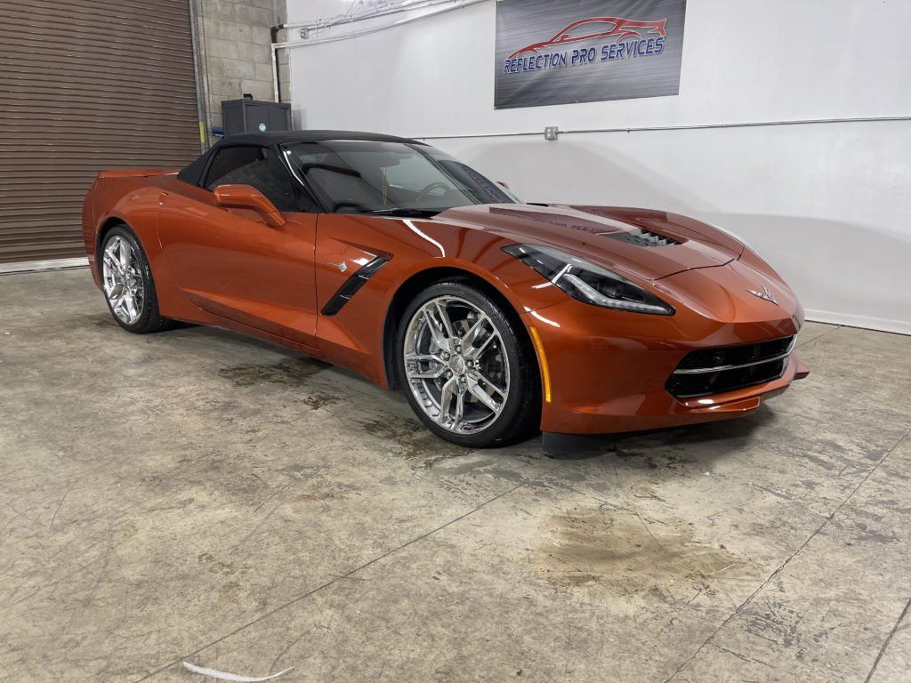 A red corvette convertible is parked in a garage.