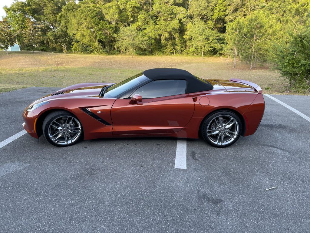A red corvette convertible is parked in a parking lot.
