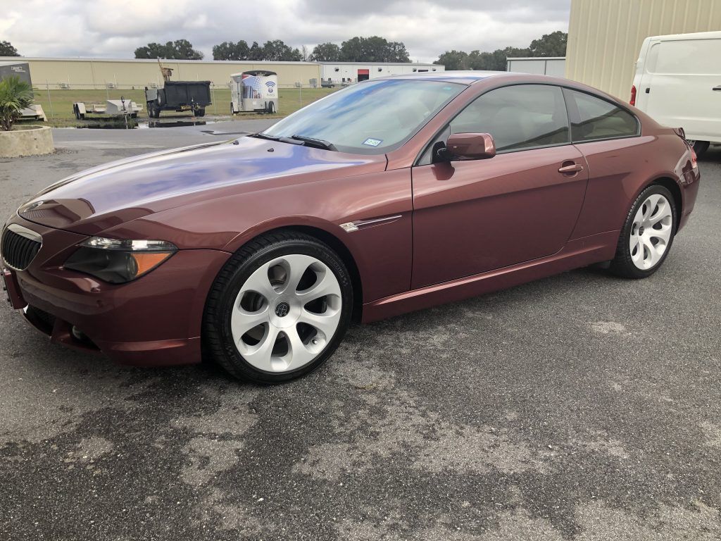 A maroon bmw 6 series coupe is parked in a parking lot.