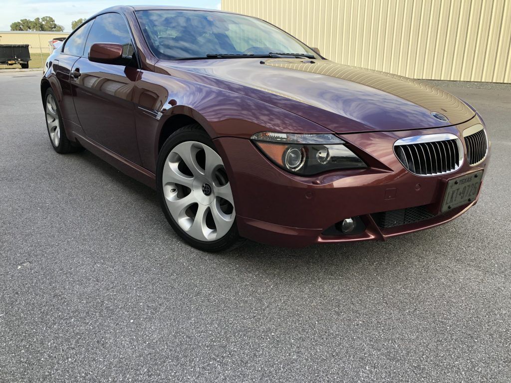 A red bmw 6 series coupe is parked in front of a building.