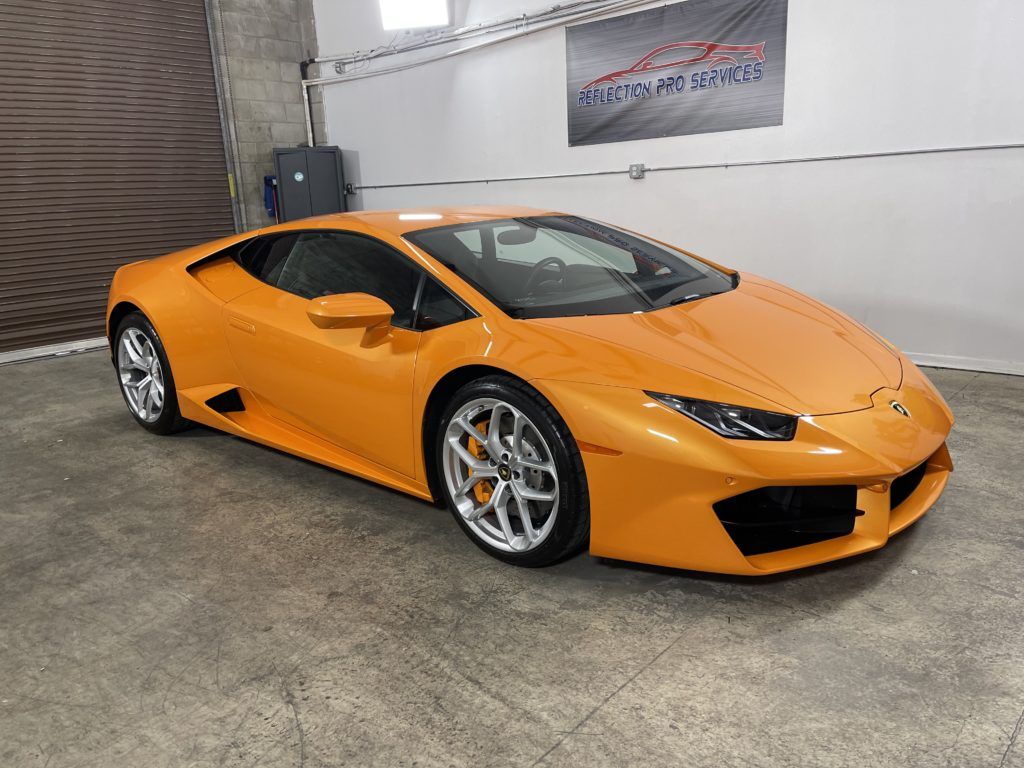 An orange lamborghini huracan is parked in a garage.