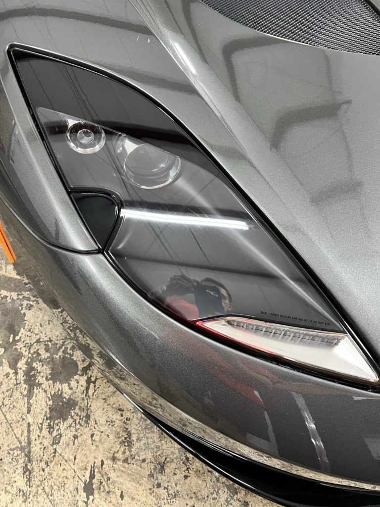 A close up of a car 's headlight in a garage.