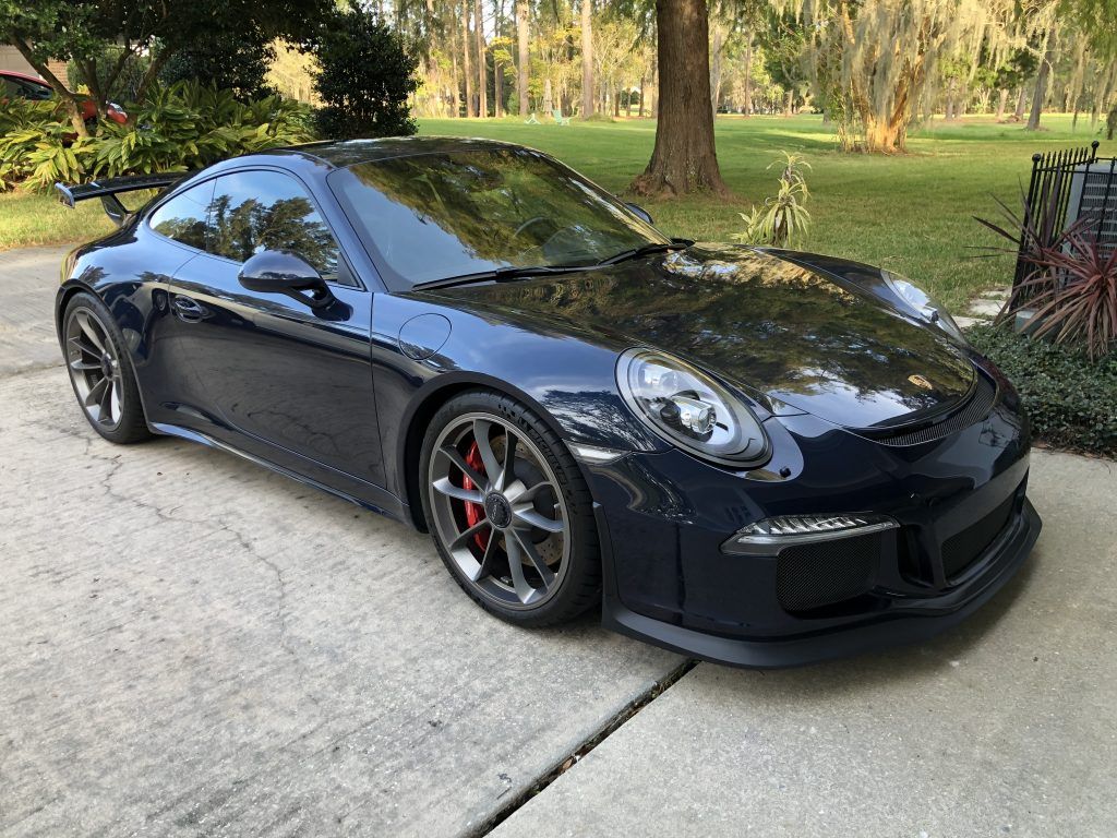 A black porsche 911 gt3 is parked in a driveway.