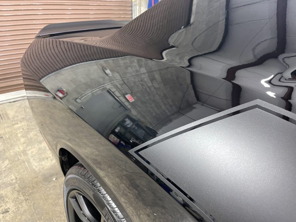 A black car is parked in a garage with the hood up.