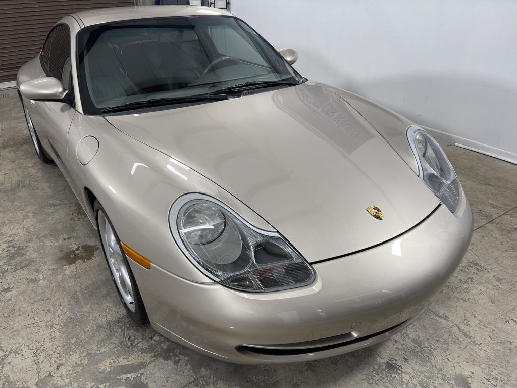 A silver porsche 911 is parked in a garage.