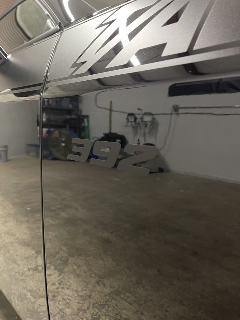 A car is parked in a garage with a reflection of a sign in the mirror.