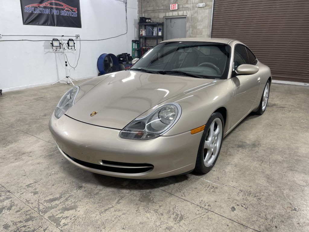 A gold porsche 911 is parked in a garage.