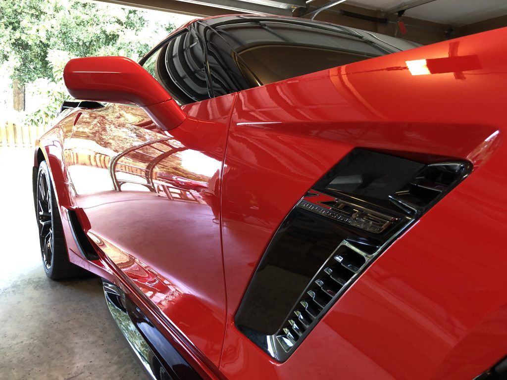 A red sports car is parked in a garage.