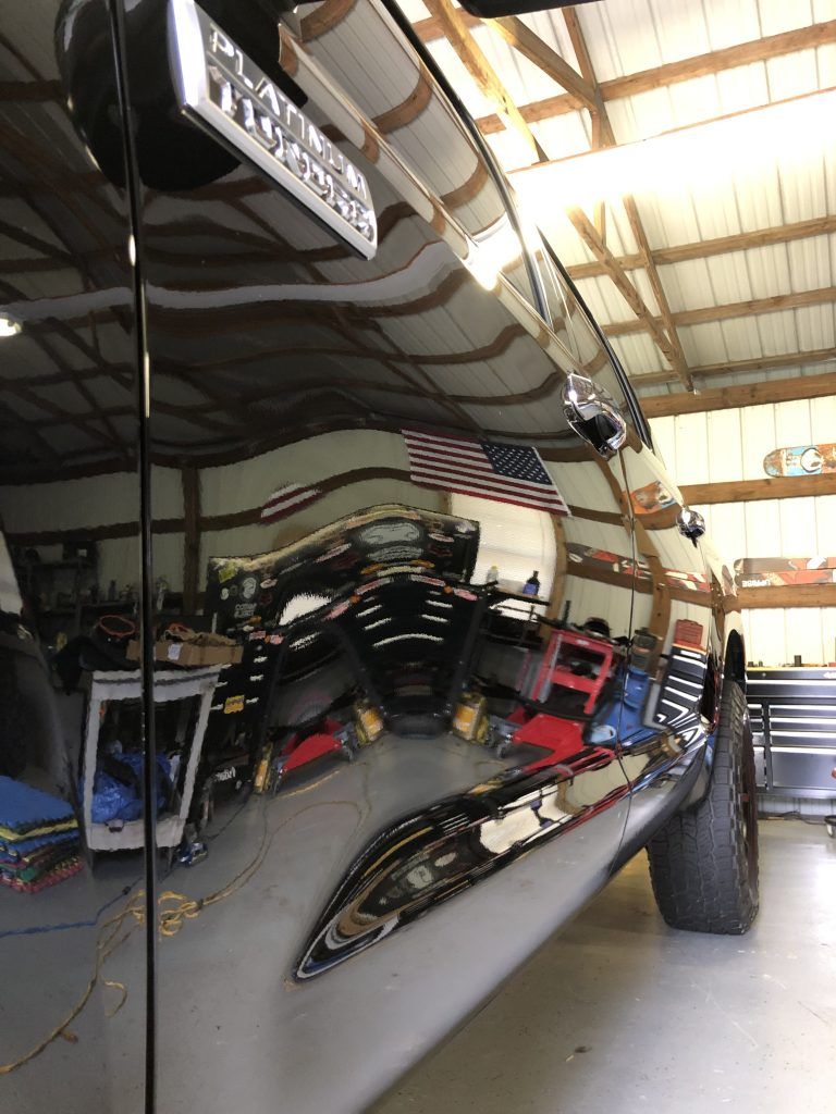 A black truck is parked in a garage with an american flag on the side.