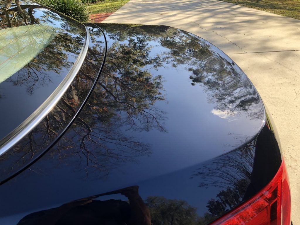 A black car is parked on the side of a road.
