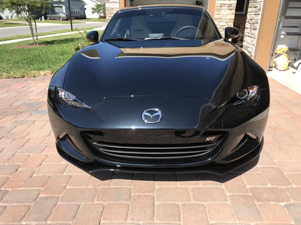 A black sports car is parked on a brick driveway