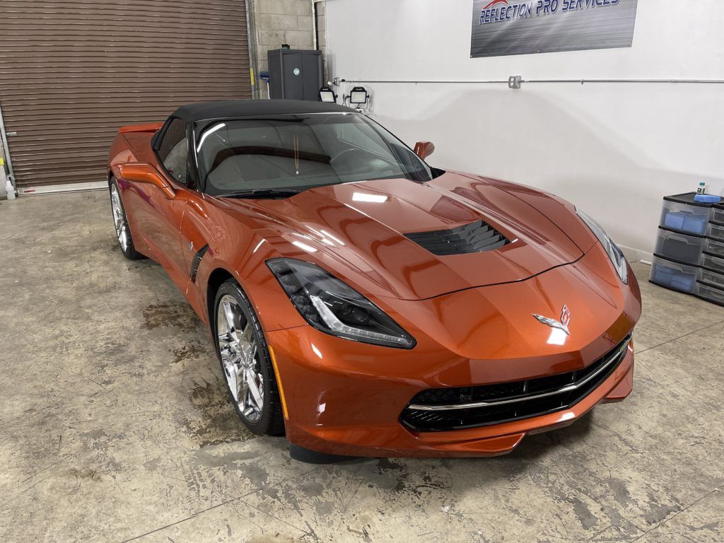 A red corvette convertible is parked in a garage.