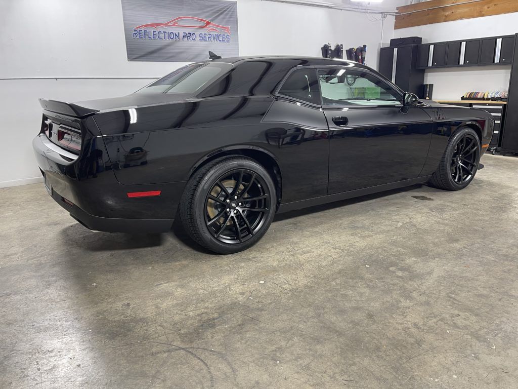 A black dodge challenger is parked in a garage.