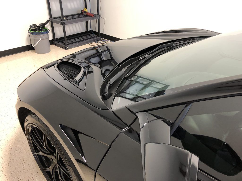 A black sports car is parked in a garage.