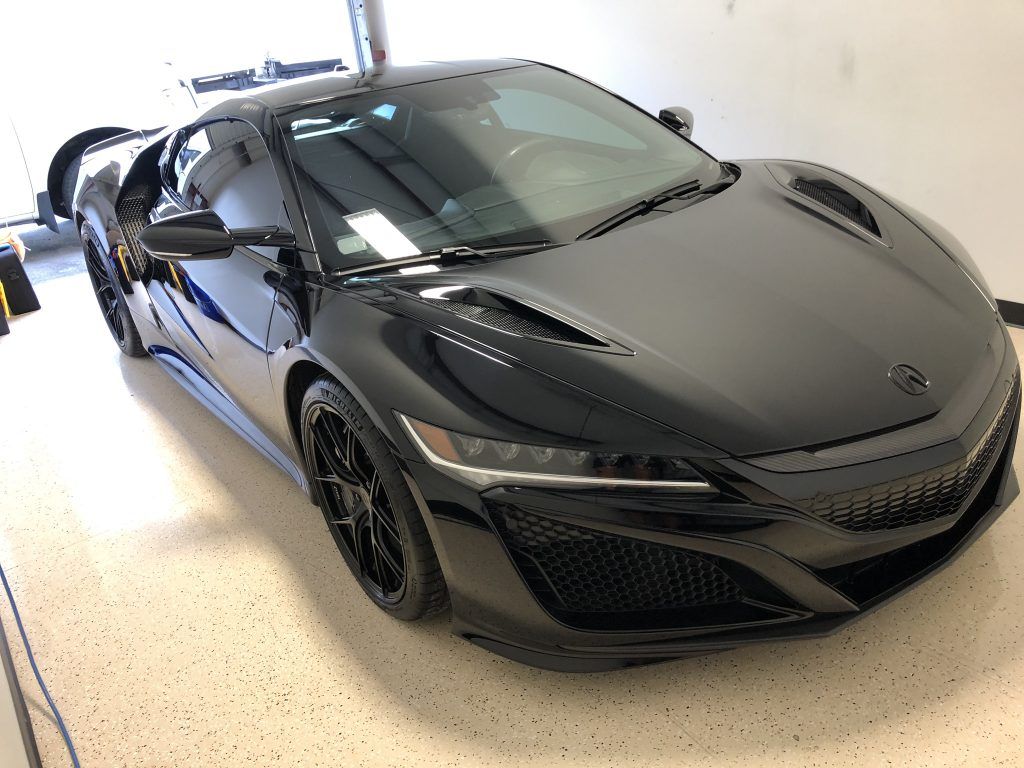 A black sports car is parked in a garage.
