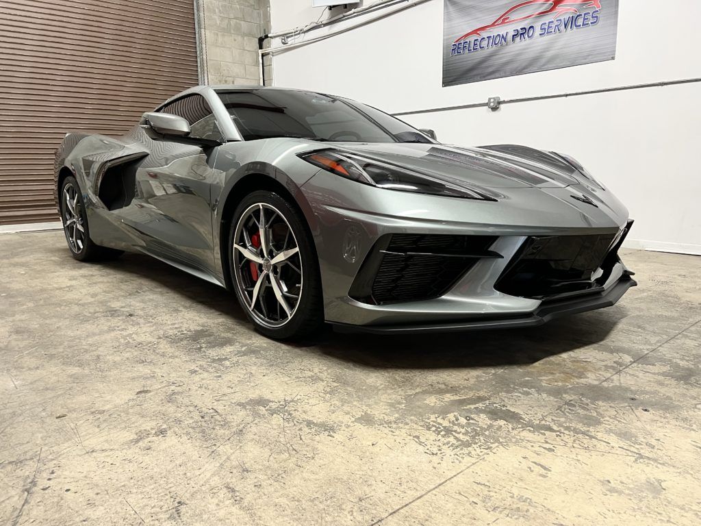 A gray sports car is parked in a garage.
