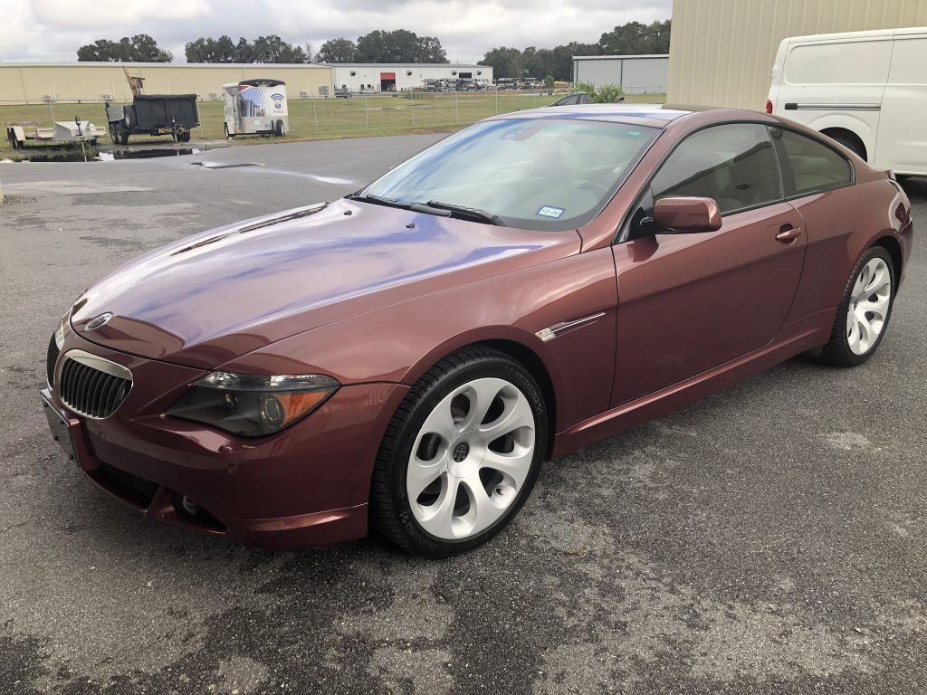 A red bmw 6 series coupe is parked in a parking lot.
