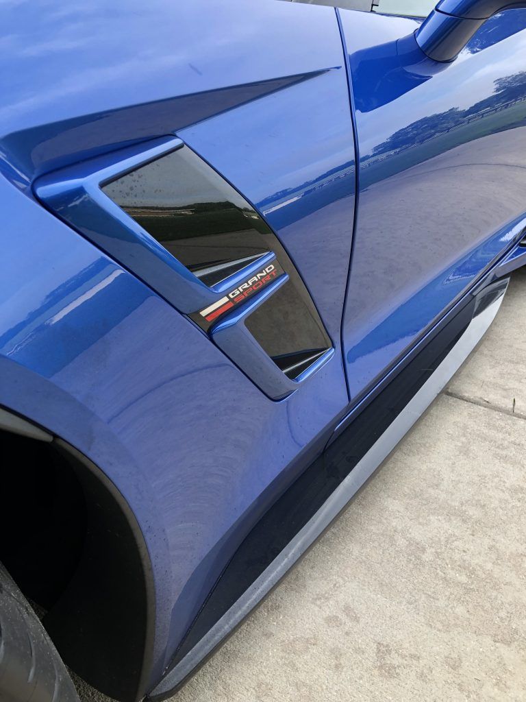 A blue sports car is parked on the side of the road.