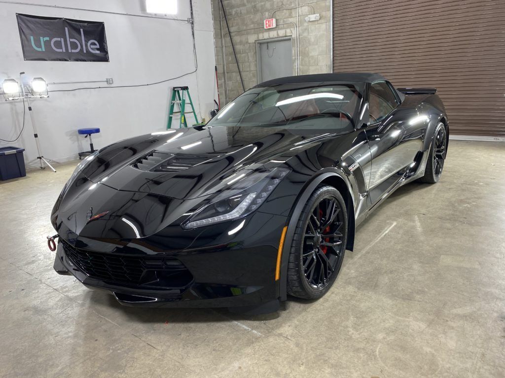A black sports car is parked in a garage.