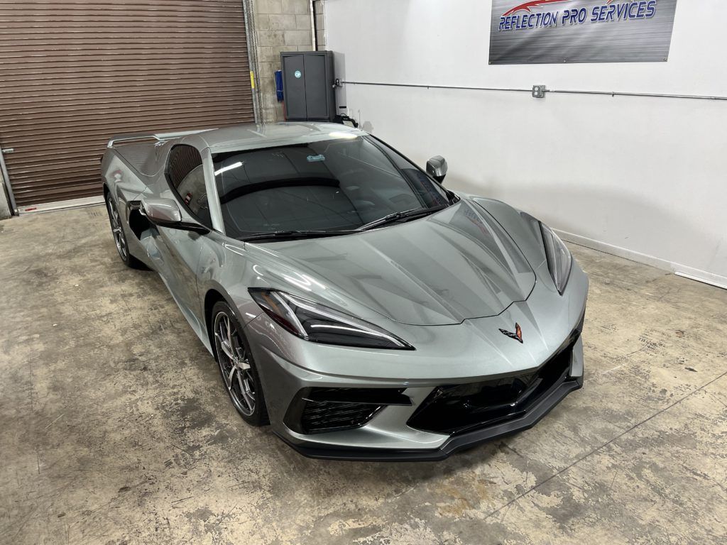 A gray corvette is parked in a garage.
