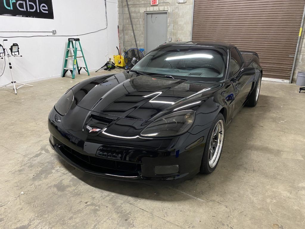 A black sports car is parked in a garage.