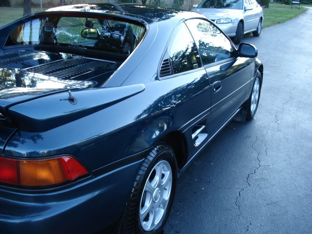 A blue car is parked on the side of the road