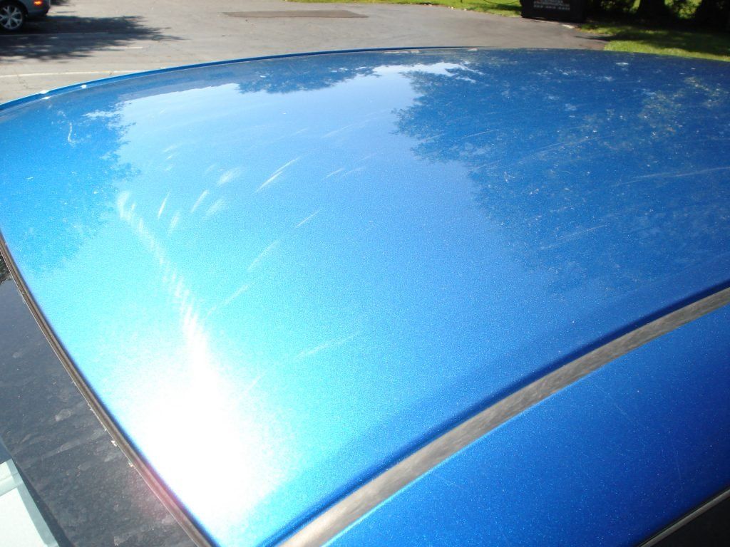 A blue car is parked in a parking lot