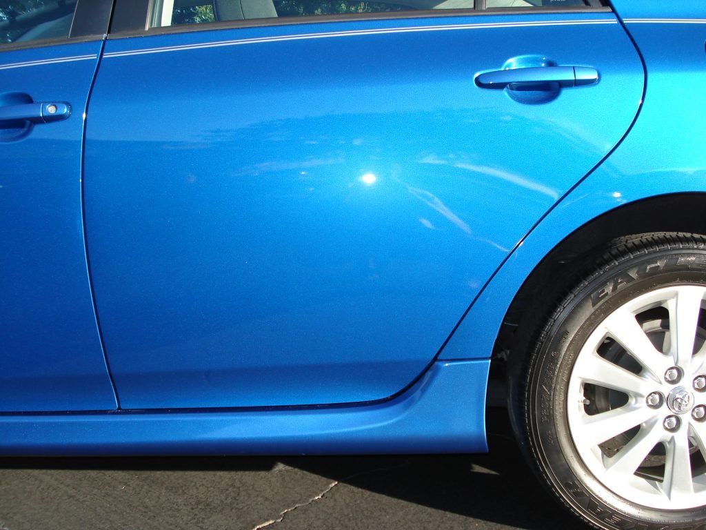 A blue car is parked on the side of the road