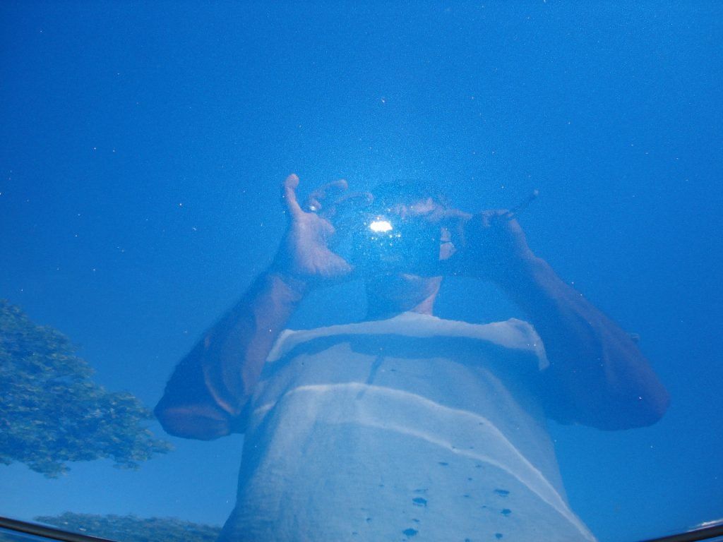 A man is taking a picture of himself in a car window.