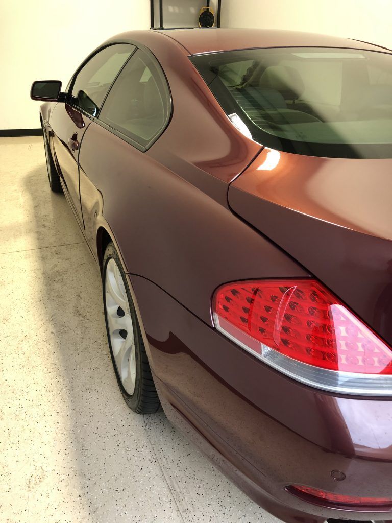 A burgundy colored car is parked in a garage