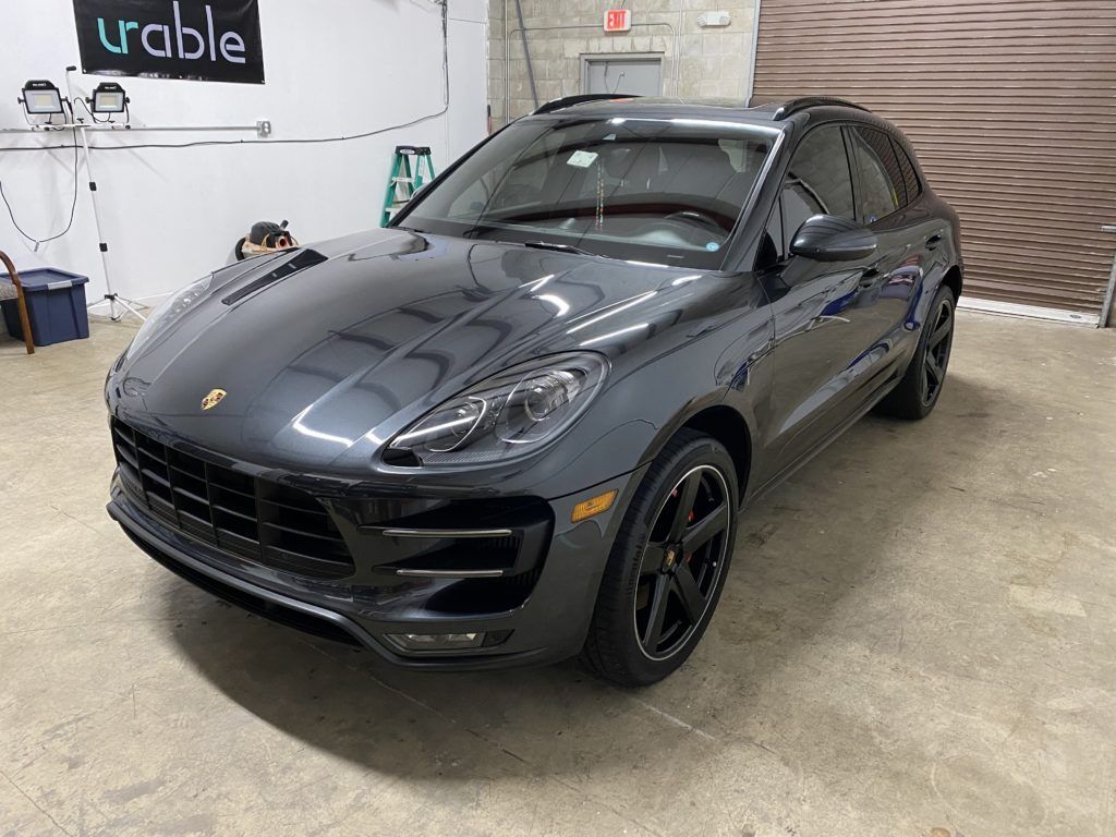 A gray porsche macan turbo is parked in a garage.