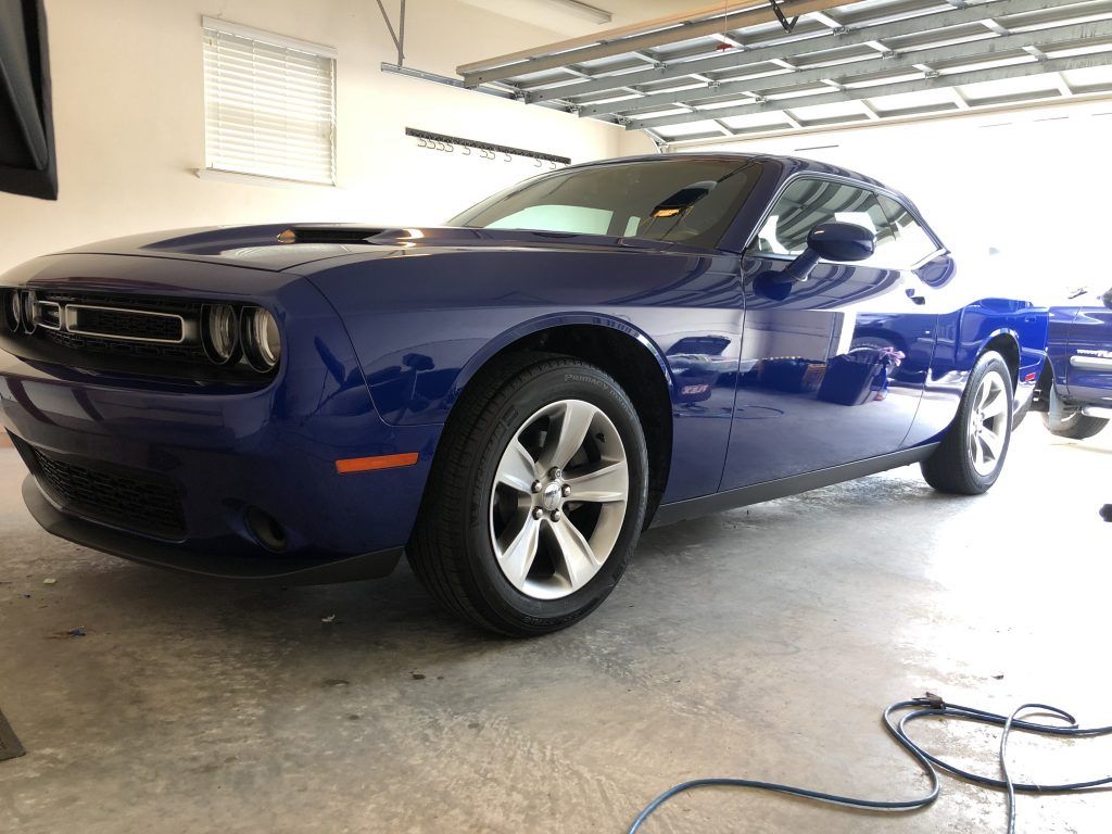 A blue dodge challenger is parked in a garage.
