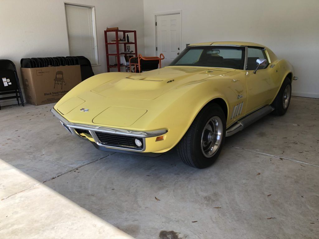 A yellow corvette is parked in a garage.