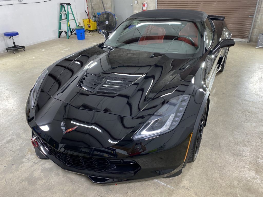 A black corvette convertible is parked in a garage.
