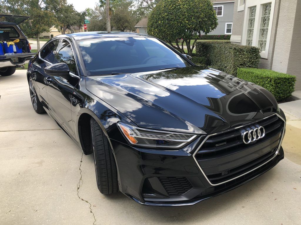 A black audi a7 is parked in a driveway in front of a house.