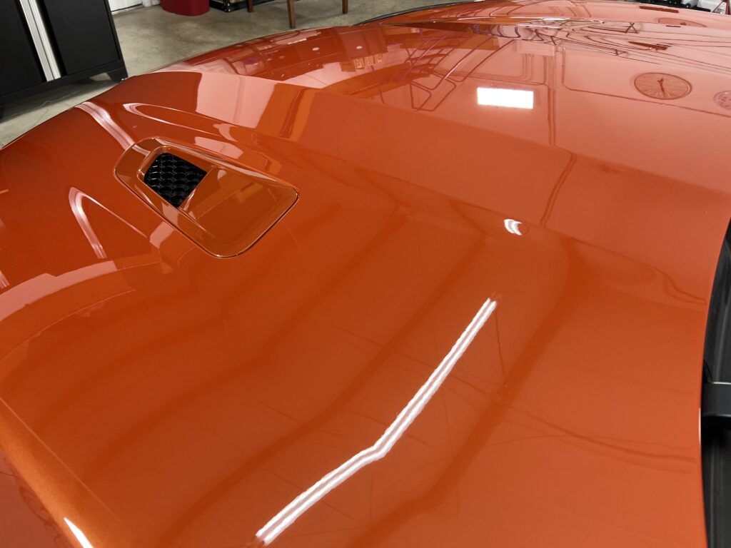 A close up of the hood of an orange car in a garage.
