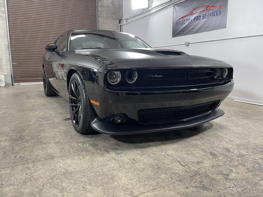 A black dodge challenger is parked in a garage.