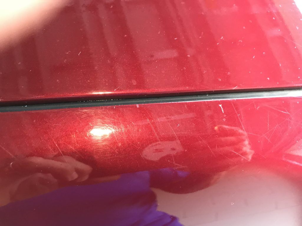 A person is taking a picture of a red car.