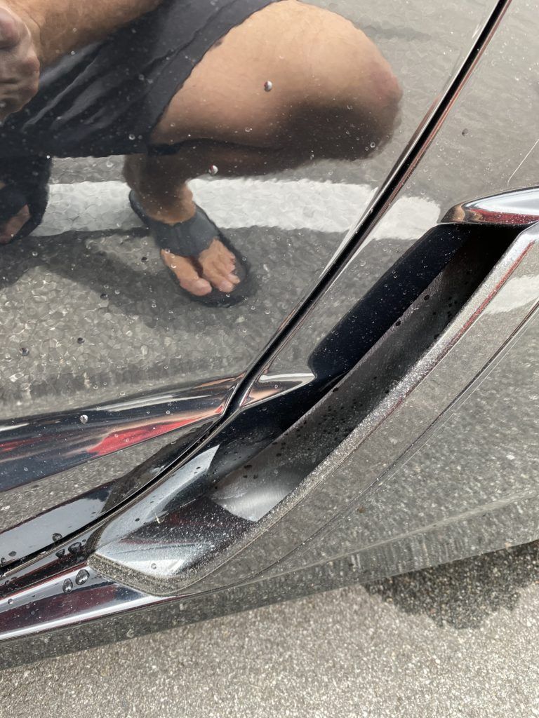 A person is kneeling down in front of a car.