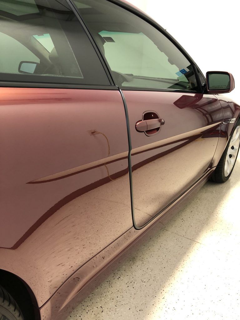 A red car is parked in a garage with a white floor.